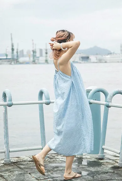 海辺で播州織の水色ワンピースを着た女性